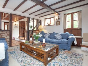 A cozy living room with a blue sofa, wooden coffee table, and patterned rug.