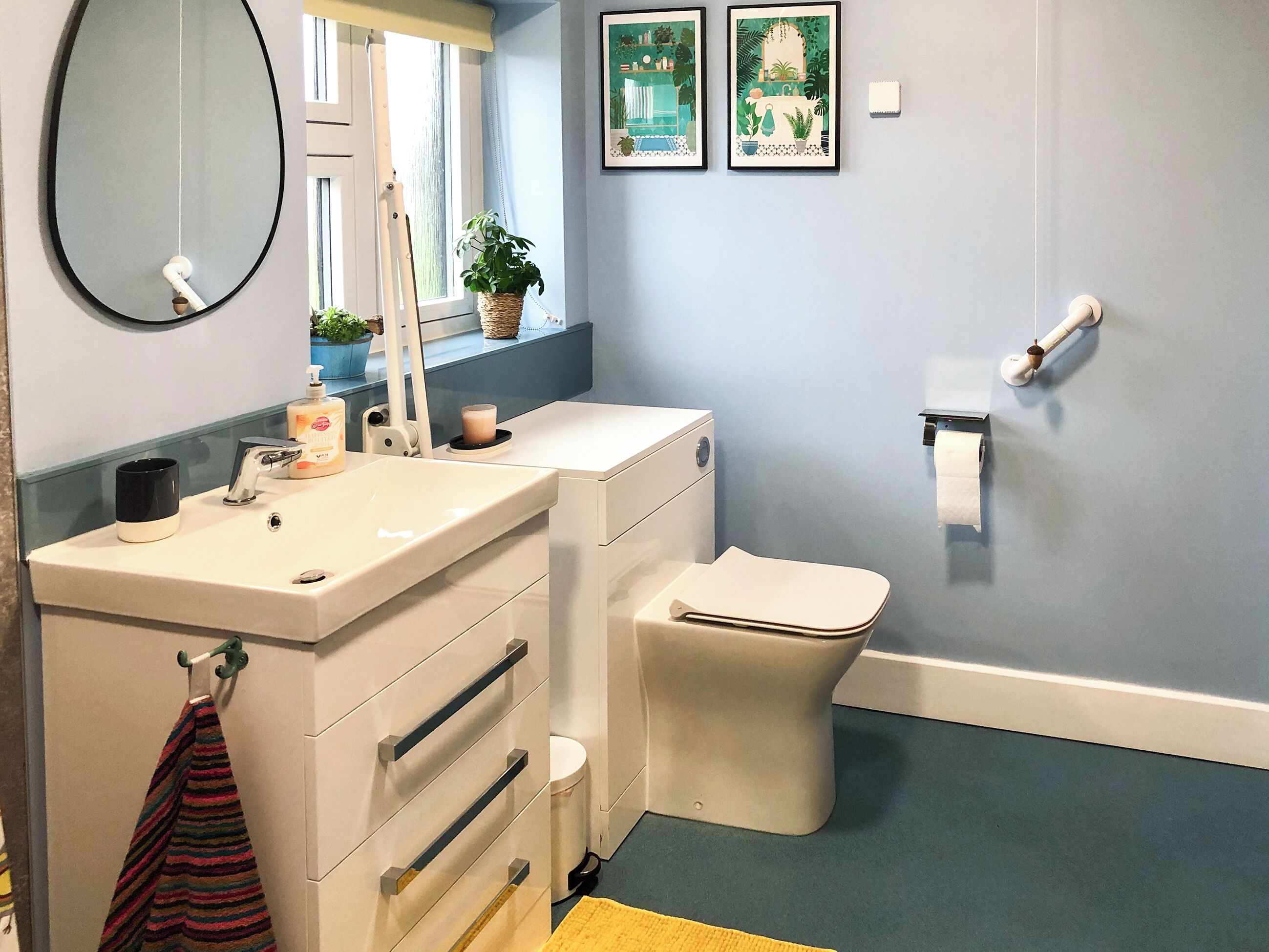 A bathroom with a white sink, mirror, toilet, and a towel rack.