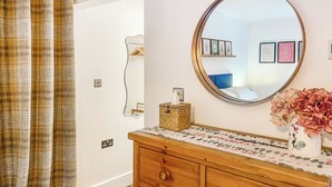 A bathroom with a wooden vanity, a round mirror, a vase with flowers, and a checkered curtain. - 2 bedroom accommodation in Hadlow, near Tonbridge (Hadlow, near Tonbridge)