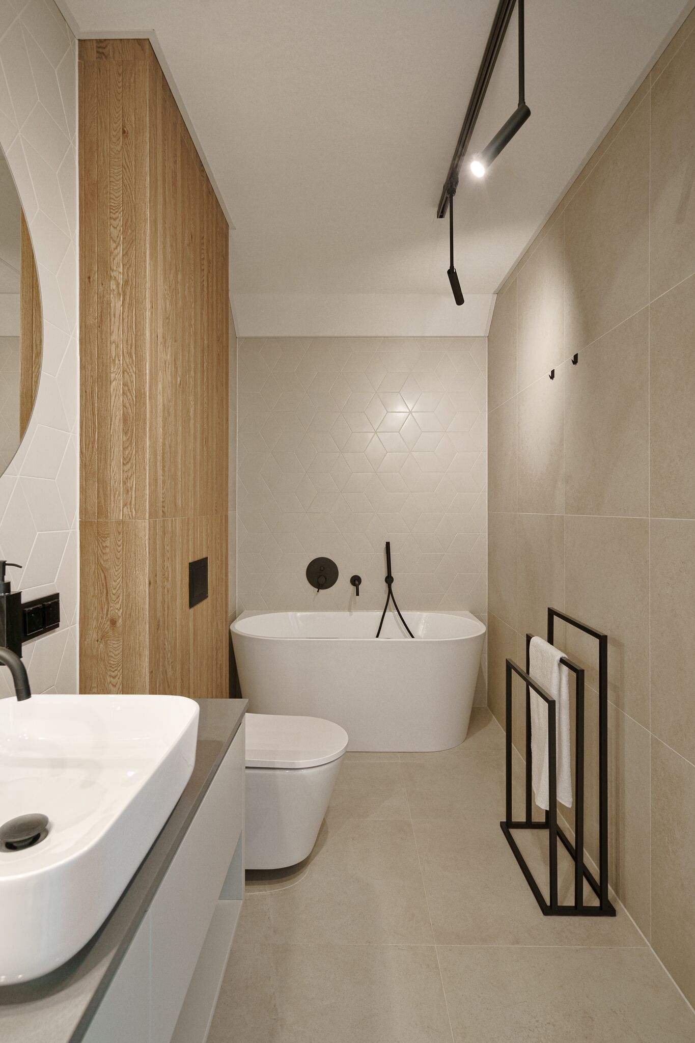 A modern bathroom with a freestanding bathtub, a large mirror, and a wooden accent wall.