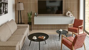 A modern living room with a sofa, two armchairs, a coffee table, a TV, and a lamp. - Korona Bieszczad Premium Apartments (Cisna)