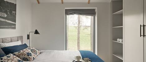Un dormitorio con cama, ventana con vistas a árboles, armario y pared con un mapa.