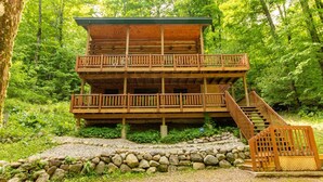 Une cabane en rondins à deux étages, dotée d’un balcon et d’un escalier menant à l’étage supérieur.
