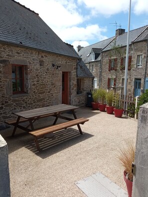 A stone building with a wooden picnic table and potted plants.
