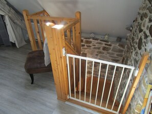 A room with a stone wall, a wooden chair, and a white baby gate.