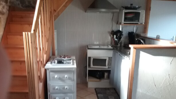 Ett kök med spis, ugn, mikrovågsugn och en bänkskiva i trä.