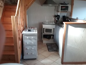 A kitchen with a stove, oven, microwave, and a wooden counter.