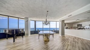 Una habitació àmplia amb taula de dinar, un piano de cua i vistes a l'oceà.