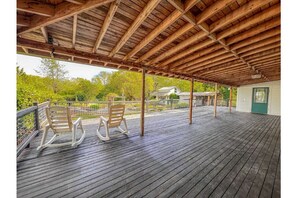 Relax in a serene outdoor space with two comfortable rocking chairs on a rustic deck surrounded by lush greenery.