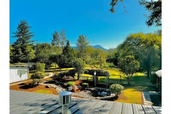 Relax in a serene garden setting surrounded by lush greenery and a majestic mountain range.