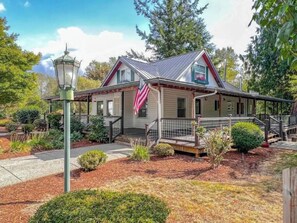 Stroll through the beautifully landscaped garden surrounding this charming two-story house with a gabled roof and inviting front porch.