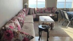 Un salón con sofá, mesa de centro y vista al mar a través de amplios ventanales.