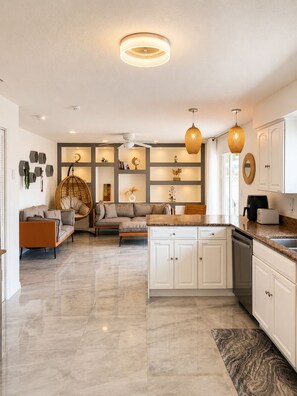 A modern kitchen with white cabinetry, a marble countertop, and a built-in dishwasher. - Tropical Vacation POOL Home in Melbourne, 7 mins to Beach (Melbourne)