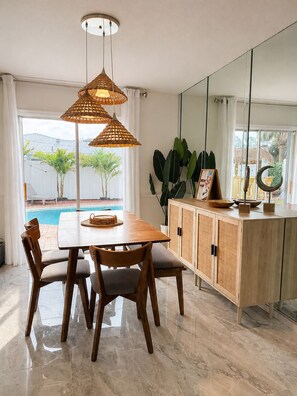 A dining area with a wooden table and chairs, a glass cabinet, and a view of a swimming pool. - Tropical Vacation POOL Home in Melbourne, 7 mins to Beach (Melbourne)
