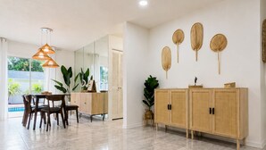 A spacious room with a dining area, a wooden cabinet, and a large mirror. - Tropical Vacation POOL Home in Melbourne, 7 mins to Beach (Melbourne)