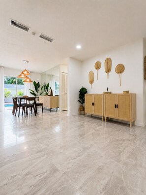 A spacious room with a dining area, a wooden cabinet, and a large mirror. - Tropical Vacation POOL Home in Melbourne, 7 mins to Beach (Melbourne)