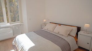 Une chambre à coucher avec un lit, des tables de chevet et une fenêtre.