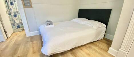 A bedroom with a bed, a nightstand, and a wall-mounted sign.