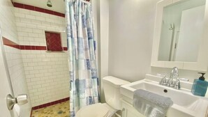 Une salle de bain équipée d’une douche, de toilettes, d’un lavabo et d’un miroir.