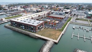 An aerial view of a waterfront property with a large building, a marina, and a parking lot. - Condo with Lake & Cedar Point View (Sandusky)