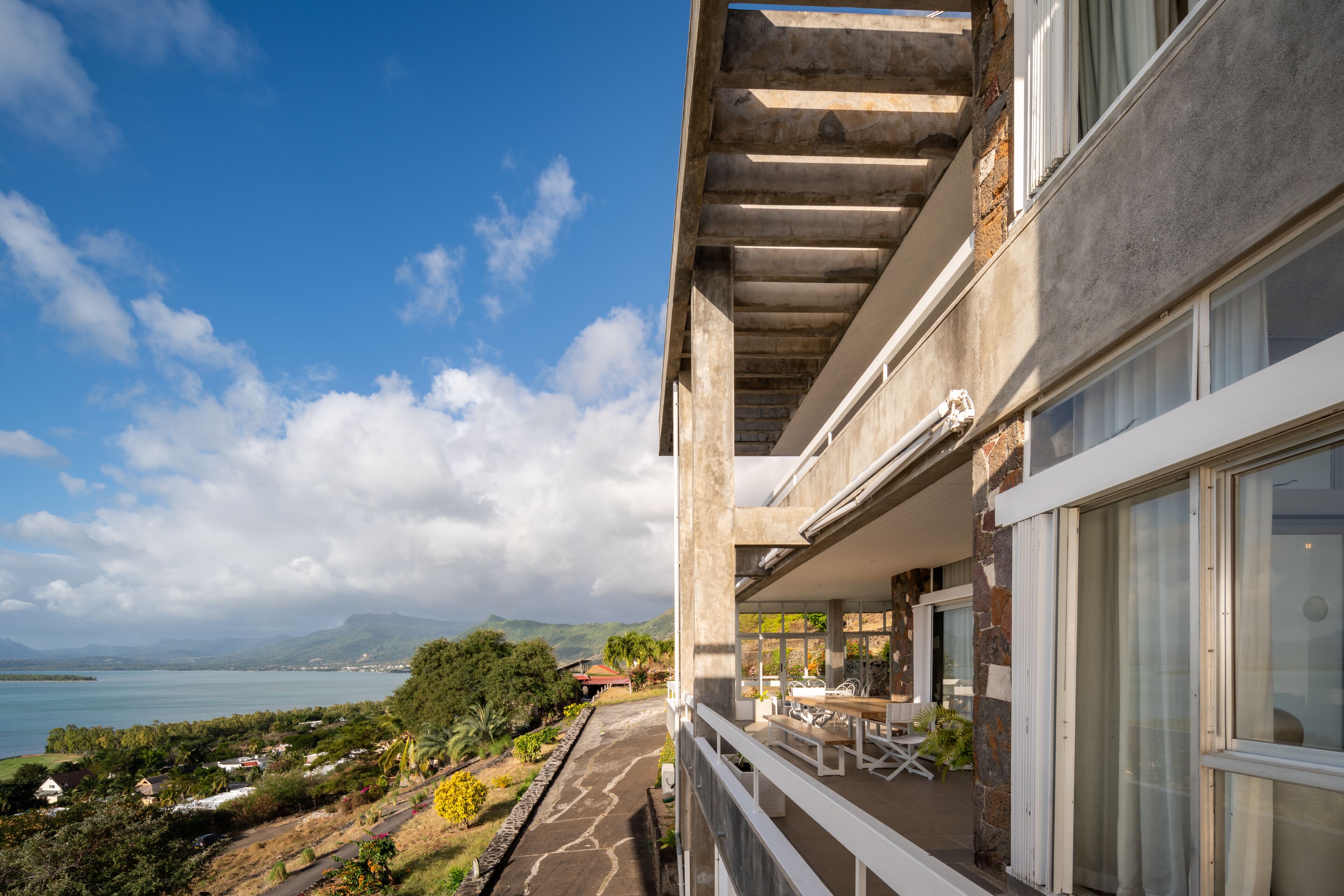 A modern building with a balcony overlooking a scenic view of a lake and mountains.