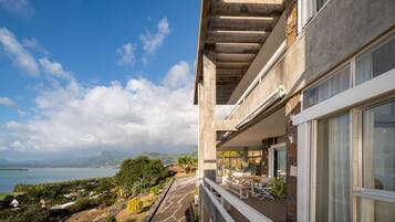A modern building with a balcony overlooking a scenic view of a lake and mountains.