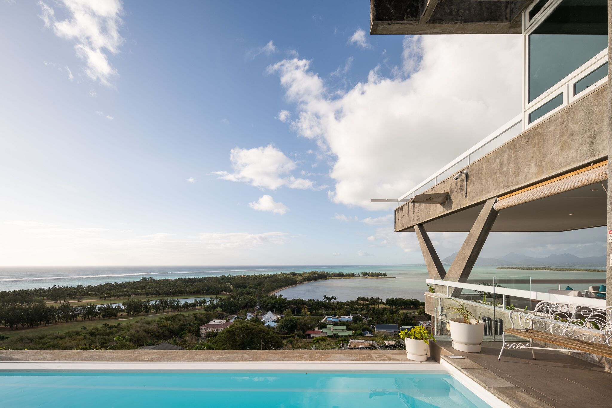 A modern building with a pool overlooking a coastal landscape.