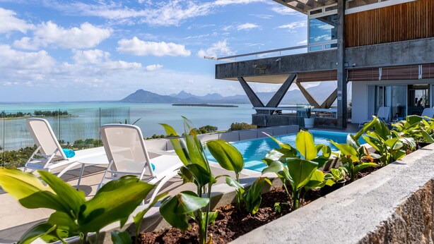 Ein moderner Poolbereich im Freien mit Liegestühlen und Blick auf den Ozean.