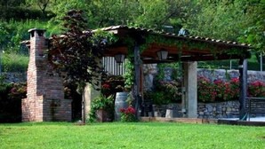 A brick chimney, a pergola with climbing plants, and a stone wall with flowers.