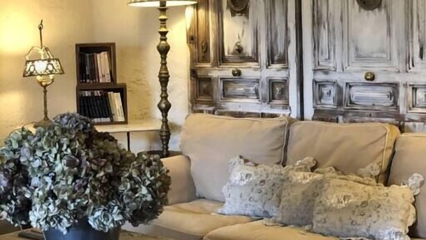 A living room with a beige sofa, a coffee table, a lamp, and a decorative wall panel.