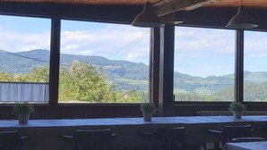 A dining area with large windows overlooking a mountainous landscape.