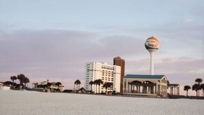 Een hotel aan het strand, met een opvallende watertoren en een groot gebouw op de achtergrond.