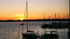 Een jachthaven in de zonsondergang, met boten aanmeren, een heldere lucht en een verre kustlijn.