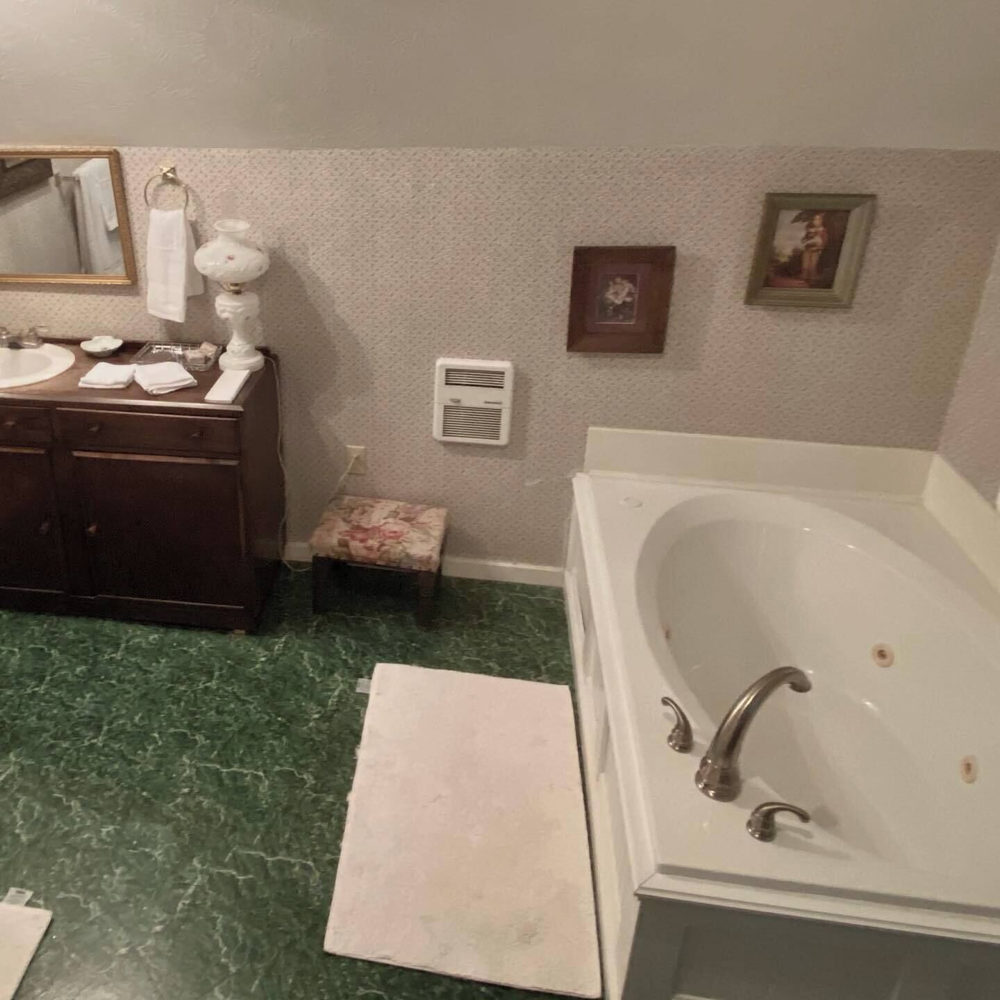 A bathroom with a marble floor, a large bathtub, a sink, and a vanity with a mirror.