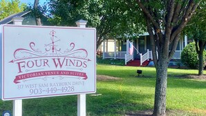 Señal que indica 'Four Winds Victorian Venue and Suites', con una dirección y número de teléfono.