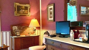 Una habitación con escritorio, silla, cómoda, lámpara, computadora y espejo.