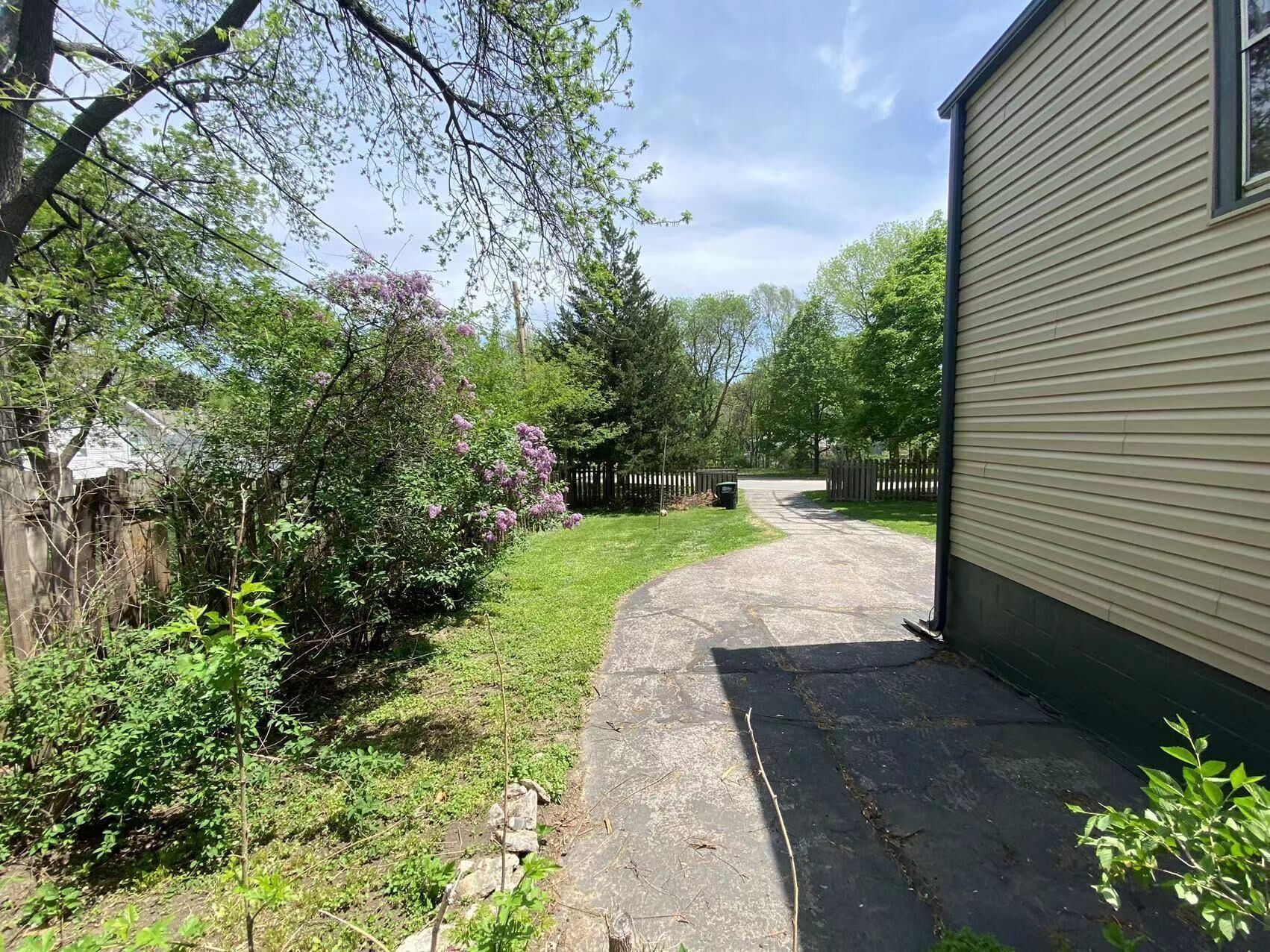 A residential backyard with a paved pathway leading to a wooden gate.
