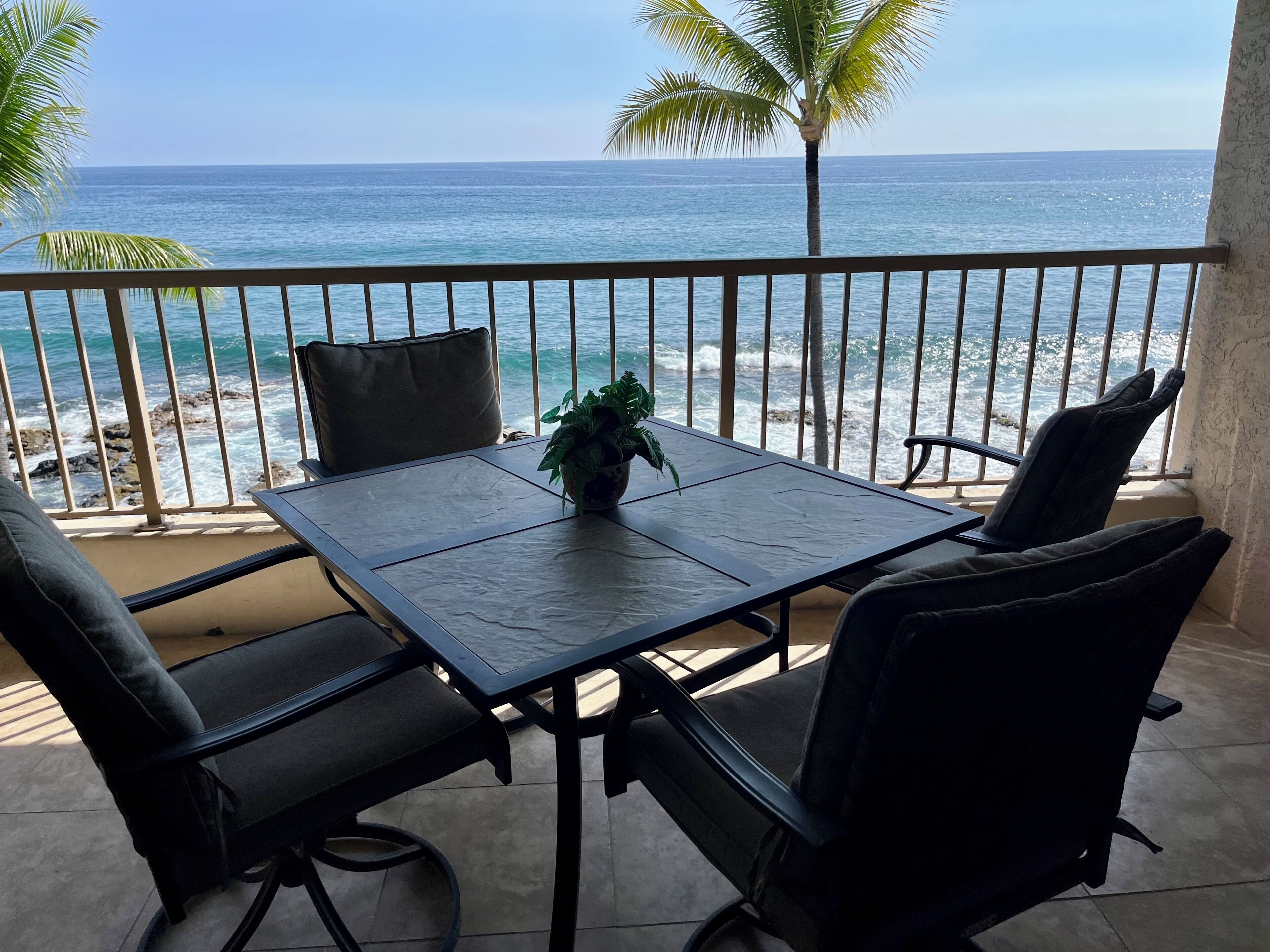 Een balkon met een tafel en stoelen, met uitzicht op een strand en de oceaan.