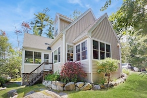 A two-story house with a front porch, a staircase, and a stone retaining wall.