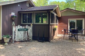 A wooden house with a porch, a sign reading "Winnipegausee," and a gravel driveway.