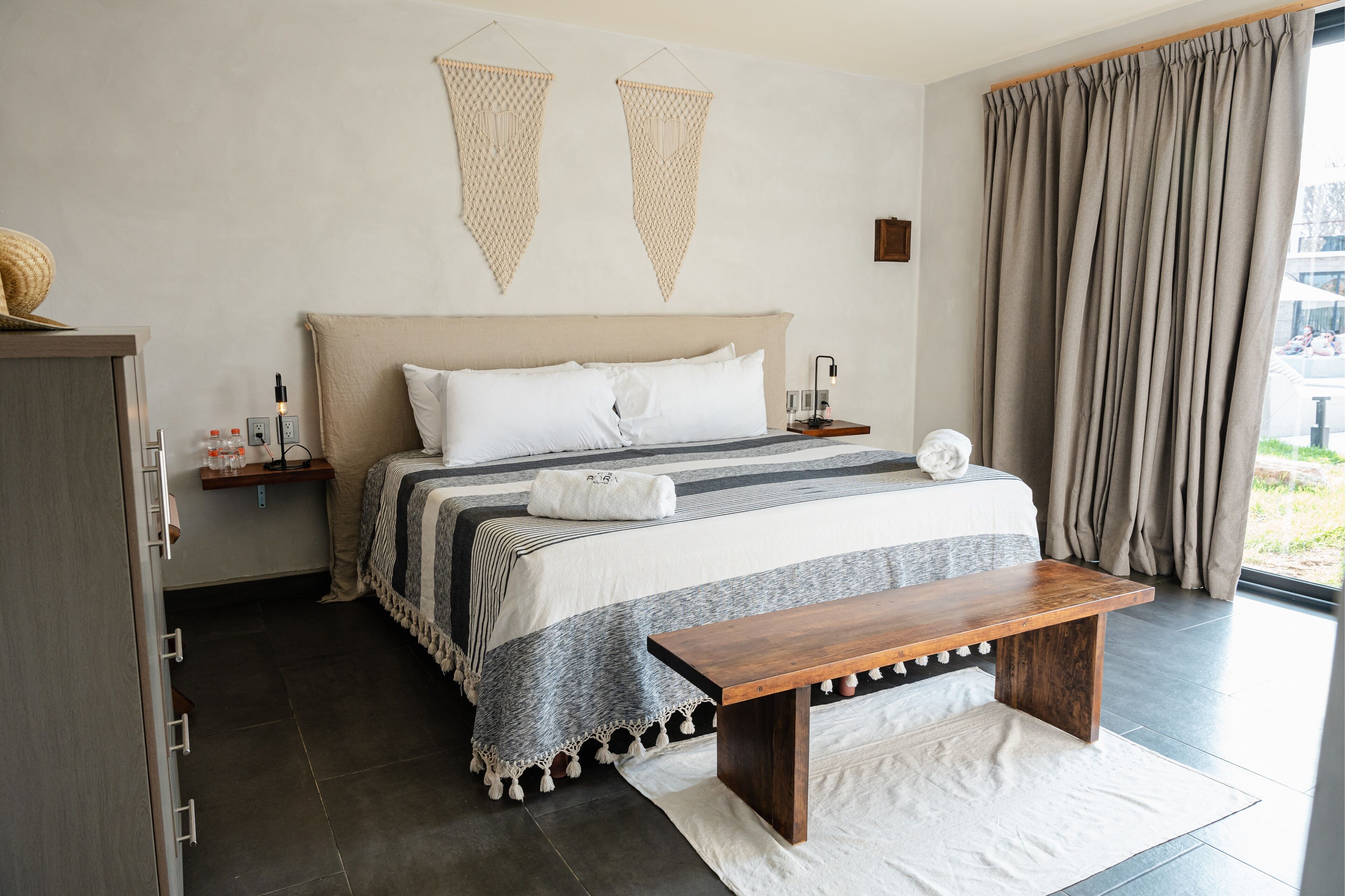Een slaapkamer met een groot bed, nachtkastjes, een bankje en uitzicht op de omgeving.