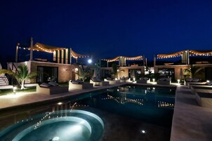 Zona de piscina con sillones de descanso e iluminación con luces colgantes.