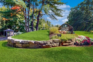 Escape to a serene retreat nestled in a lush landscape with a well-maintained lawn and charming stone wall.