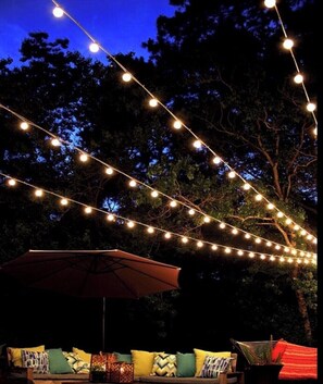 An outdoor seating area with string lights and an umbrella.