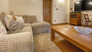 A cozy living room with a sectional sofa, a wooden coffee table, and a flat-screen TV mounted on the wall. - 2 bedroom accommodation in Hothfield (Hothfield)