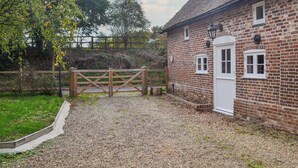 A brick building with a gravel driveway and a wooden gate. - 2 bedroom accommodation in Hothfield (Hothfield)
