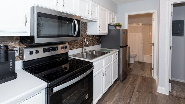 A modern kitchen with white cabinets, stainless steel appliances, and a granite countertop.