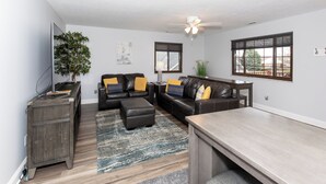 A modern living room with a sectional sofa, a wooden coffee table, and a TV on a stand.