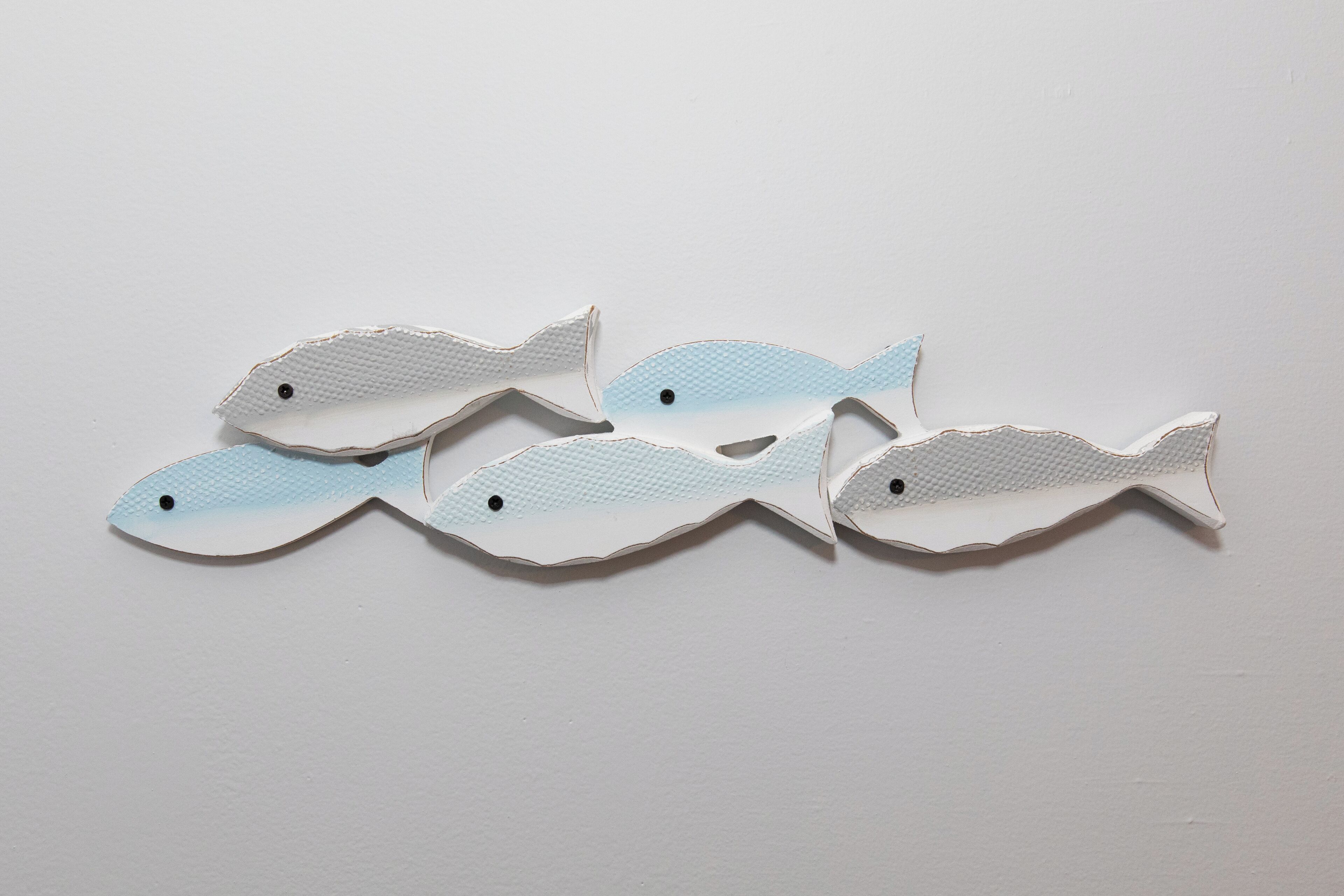 Five paper fish shapes on a plain background.