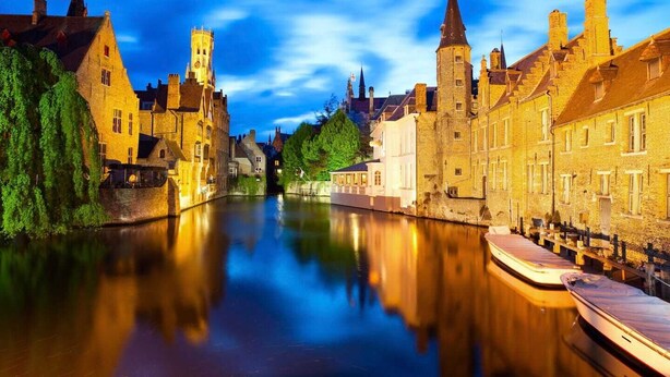 Un canal historique, bordé de bâtiments des deux côtés, dont une tour et une rangée de maisons traditionnelles.